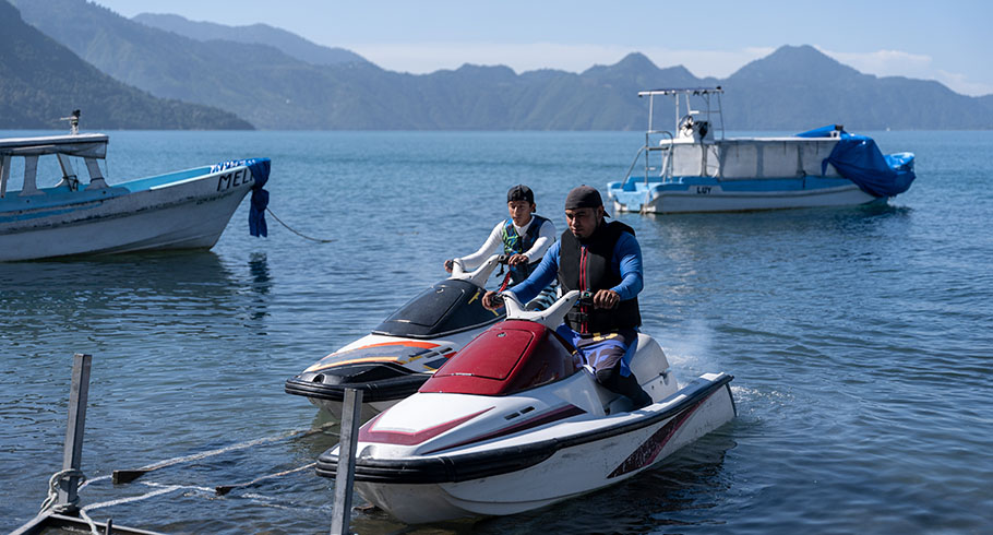 Young men lower jet skis from trailer
